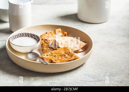 Dünne Crepes mit saurer Sahne auf weißem Teller. Konzept der russischen Küche. Stockfoto