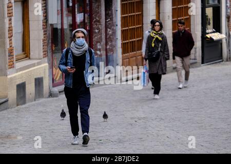 Brüssel, Belgien. März 2020. Menschen, die nach einem Ausbruch des Coronavirus schützende Gesichtsmasken tragen, machen sich im historischen Zentrum Brüssels auf den Weg. Credit: ALEXANDROS MICHAILIDIS/Alamy Live News Stockfoto