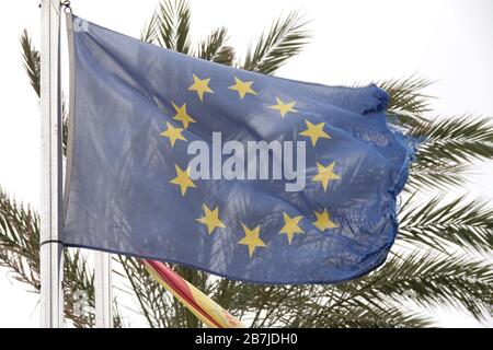 Cala Millor, Spanien. März 2020. Eine halb zerfetzte Europafahne winkt im Ferienort vor einer Palme. Credit: Bodo Marks / dpa / Alamy Live News Stockfoto