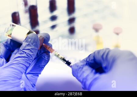Handschuhhandschuhe, die eine Spritze halten, während eine Dosis geladen wird. Konzepte der medizinischen Behandlung, Epidemie oder Impfung Stockfoto
