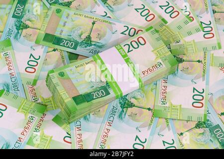 Ein Paket mit einhundert Blättern neuer russischer Banknoten in einem Bankpaket vor dem Hintergrund anderer zweirublicher Banknoten Stockfoto