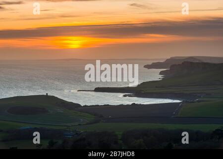 Kimmeridge, Dorset, Großbritannien. März 2020. Wetter in Großbritannien. Der Himmel leuchtet bei Sonnenuntergang von Swyre Head bei Kimmeridge an der Juraküste von Dorset aus orange und blickt nach einem Tag mit warmem Sonnenschein und klarem blauen Himmel nach Westen über die Kimmeridge Bay und die Warbarrow Bay. Bildnachweis: Graham Hunt/Alamy Live News Stockfoto