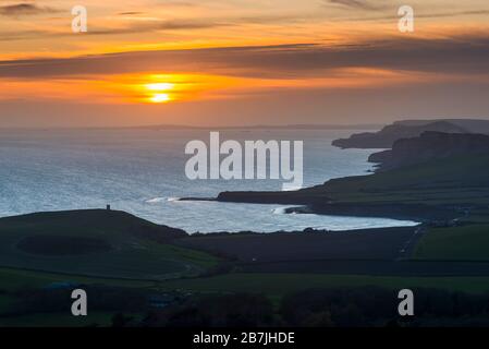 Kimmeridge, Dorset, Großbritannien. März 2020. Wetter in Großbritannien. Der Himmel leuchtet bei Sonnenuntergang von Swyre Head bei Kimmeridge an der Juraküste von Dorset aus orange und blickt nach einem Tag mit warmem Sonnenschein und klarem blauen Himmel nach Westen über die Kimmeridge Bay und die Warbarrow Bay. Bildnachweis: Graham Hunt/Alamy Live News Stockfoto