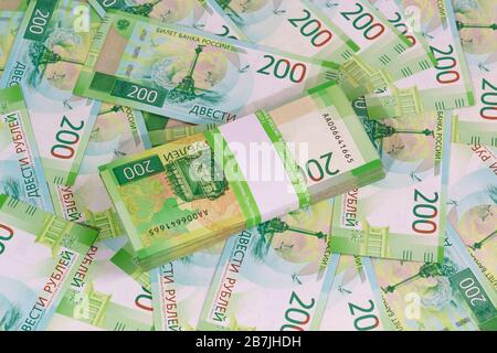 Ein neues Bankpaket mit hundert Blättern russischer Banknoten vor dem Hintergrund anderer zweirublicher Banknoten. Business still Life Stockfoto