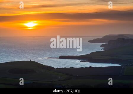 Kimmeridge, Dorset, Großbritannien. März 2020. Wetter in Großbritannien. Der Himmel leuchtet bei Sonnenuntergang von Swyre Head bei Kimmeridge an der Juraküste von Dorset aus orange und blickt nach einem Tag mit warmem Sonnenschein und klarem blauen Himmel nach Westen über die Kimmeridge Bay und die Warbarrow Bay. Bildnachweis: Graham Hunt/Alamy Live News Stockfoto