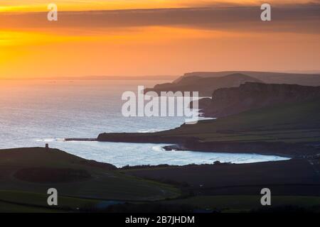 Kimmeridge, Dorset, Großbritannien. März 2020. Wetter in Großbritannien. Der Himmel leuchtet bei Sonnenuntergang von Swyre Head bei Kimmeridge an der Juraküste von Dorset aus orange und blickt nach einem Tag mit warmem Sonnenschein und klarem blauen Himmel nach Westen über die Kimmeridge Bay und die Warbarrow Bay. Bildnachweis: Graham Hunt/Alamy Live News Stockfoto