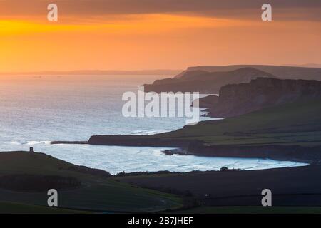 Kimmeridge, Dorset, Großbritannien. März 2020. Wetter in Großbritannien. Der Himmel leuchtet bei Sonnenuntergang von Swyre Head bei Kimmeridge an der Juraküste von Dorset aus orange und blickt nach einem Tag mit warmem Sonnenschein und klarem blauen Himmel nach Westen über die Kimmeridge Bay und die Warbarrow Bay. Bildnachweis: Graham Hunt/Alamy Live News Stockfoto