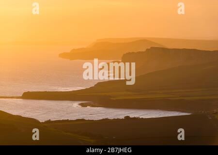 Kimmeridge, Dorset, Großbritannien. März 2020. Wetter in Großbritannien. Der Himmel leuchtet bei Sonnenuntergang von Swyre Head bei Kimmeridge an der Juraküste von Dorset aus orange und blickt nach einem Tag mit warmem Sonnenschein und klarem blauen Himmel nach Westen über die Kimmeridge Bay und die Warbarrow Bay. Bildnachweis: Graham Hunt/Alamy Live News Stockfoto