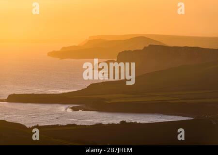 Kimmeridge, Dorset, Großbritannien. März 2020. Wetter in Großbritannien. Der Himmel leuchtet bei Sonnenuntergang von Swyre Head bei Kimmeridge an der Juraküste von Dorset aus orange und blickt nach einem Tag mit warmem Sonnenschein und klarem blauen Himmel nach Westen über die Kimmeridge Bay und die Warbarrow Bay. Bildnachweis: Graham Hunt/Alamy Live News Stockfoto