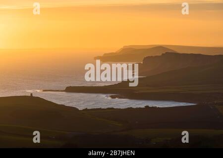 Kimmeridge, Dorset, Großbritannien. März 2020. Wetter in Großbritannien. Der Himmel leuchtet bei Sonnenuntergang von Swyre Head bei Kimmeridge an der Juraküste von Dorset aus orange und blickt nach einem Tag mit warmem Sonnenschein und klarem blauen Himmel nach Westen über die Kimmeridge Bay und die Warbarrow Bay. Bildnachweis: Graham Hunt/Alamy Live News Stockfoto