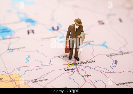 Figur des Geschäftsmannes mit Koffer, der auf einer Karte Russlands eine medizinische Maske trägt. Stockfoto