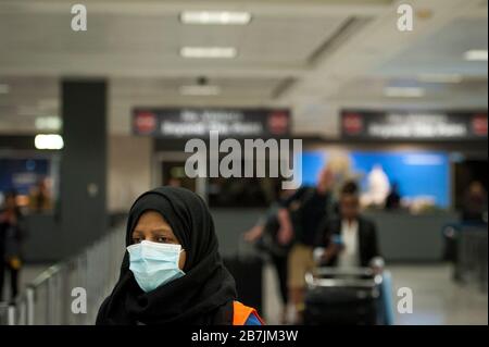 Ein Dulles International Airport Worker unterstützt Passagiere bei ihrer Ankunft aus Dubai nach einem 14-stündigen Flug auf Emirates-Flug 231 am internationalen Terminal des Dulles International Airport in Dulles, Virginia, Montag, 16. März 2020. Einige Leute ergreifen die Vorsorge, Gesichtsmasken zu tragen, wenn sie ankommen, um von Familie und Freunden begrüßt zu werden. Kredit: Rod Lamkey/CNP /MediaPunch Stockfoto