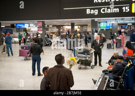 Ein Mann wartet mit einem Blumenstrauß, als Passagiere am internationalen Terminal am Dulles International Airport in Dulles, Virginia, Montag, 16. März 2020 ankommen. Einige Leute ergreifen die Vorsorge, Gesichtsmasken zu tragen, wenn sie ankommen, um von Familie und Freunden begrüßt zu werden. Kredit: Rod Lamkey/CNP weltweit Stockfoto