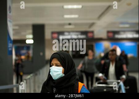 Ein Dulles International Airport Worker unterstützt Passagiere bei ihrer Ankunft aus Dubai nach einem 14-stündigen Flug auf Emirates-Flug 231 am internationalen Terminal des Dulles International Airport in Dulles, Virginia, Montag, 16. März 2020. Einige Leute ergreifen die Vorsorge, Gesichtsmasken zu tragen, wenn sie ankommen, um von Familie und Freunden begrüßt zu werden. Kredit: Rod Lamkey/CNP weltweit Stockfoto