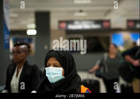 Ein Dulles International Airport Worker unterstützt Passagiere bei ihrer Ankunft aus Dubai nach einem 14-stündigen Flug auf Emirates-Flug 231 am internationalen Terminal des Dulles International Airport in Dulles, Virginia, Montag, 16. März 2020. Einige Leute ergreifen die Vorsorge, Gesichtsmasken zu tragen, wenn sie ankommen, um von Familie und Freunden begrüßt zu werden. Kredit: Rod Lamkey/CNP weltweit Stockfoto