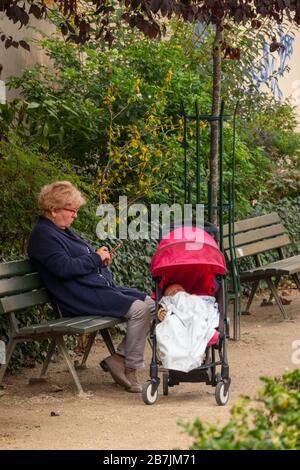 Großmutter sitzt mit Baby in einem Park in Paris Frankreich Stockfoto