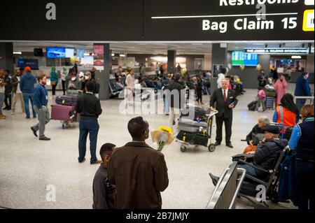 Ein Mann wartet mit einem Blumenstrauß, als Passagiere am internationalen Terminal am Dulles International Airport in Dulles, Virginia, Montag, 16. März 2020 ankommen. Einige Leute ergreifen die Vorsorge, Gesichtsmasken zu tragen, wenn sie ankommen, um von Familie und Freunden begrüßt zu werden. Kredit: Rod Lamkey/CNP /MediaPunch Stockfoto