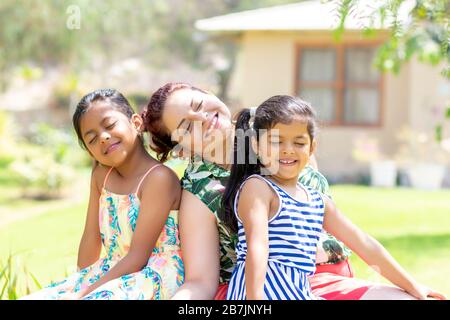 Liebe zwischen einer jungen Mutter und ihren beiden hübschen Töchtern im Freien Stockfoto