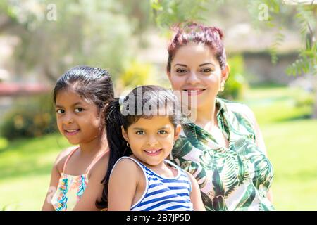 Liebe zwischen einer jungen Mutter und ihren beiden hübschen Töchtern im Freien Stockfoto