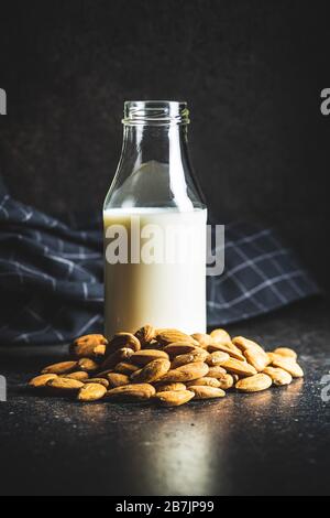 Mandeln Nüsse und Mandelmilch in Flasche auf schwarzem Küchentisch. Stockfoto