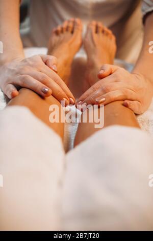 Nahaufnahme der Spa-Massagesitzung, die von einem aufmerksamen Mitarbeiter im Salon an den Beinen des Kunden gemacht wurde Stockfoto