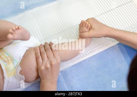 Facharzt für Kinderärzte, der die Höhe von Kleinkindern während der Screening-Untersuchung messen kann. Arzt oder Pfleger, die das Bein des Kindes halten, um die Messung zu ergreifen Stockfoto
