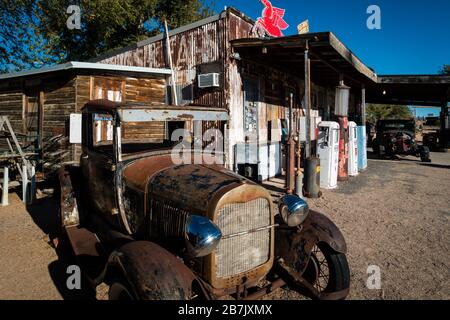 Verrosttes altes Auto, das vor der historischen, verschlechterten Tankstelle an der Route 66 in der Nähe von Seligman, Arizona steht. Sonniges Tageslicht, keine Menschen sichtbar. Stockfoto