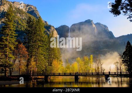 Morgennebel, der mit Yosemite über die schwingende Brücke über den Fluss Merced steigt, fällt in den Hintergrund. Yosemite-Nationalpark Kalifornien USA Stockfoto