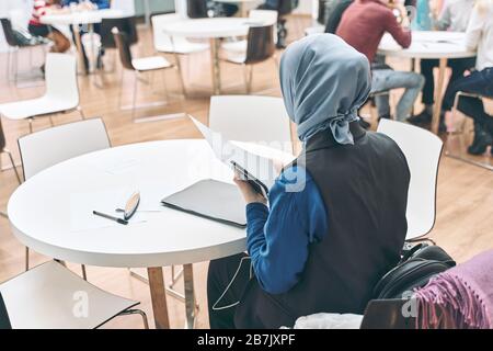 Muslimische Geschäftsfrau, die im Team mit ihren Kollegen im Büro arbeitet. Auf dem Kopf des Mädchens ist Hijab ein traditioneller muslimischer Kopfschmuck. Das Konzept von Stockfoto