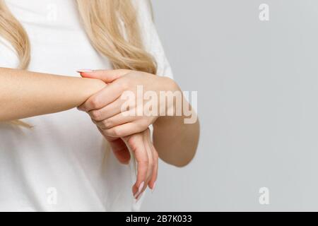 Nahaufnahme der Arme der Frau, die ihr schmerzhaftes Handgelenk hält, das durch längere Arbeiten am Computer, Laptop verursacht wurde. , neurologisches Krankheitskonzept. Taubheit der Hand Stockfoto