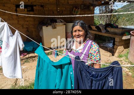 Lentuvi, Oaxaca, Mexiko - EINE Zapotec-Frau hängt ihre Wäsche an einer Linie von ihrem Haus in den Bergen der Sierra Norte. Stockfoto