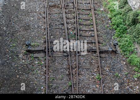 Altes Eisenbahnfoto von oben aufgenommen die Schiene fährt von unten nach oben fort. Es wurden Kieselsteine und Gras herumgeführt. Fotografiert auf einem Stockfoto