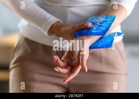 Nahaufnahme der Frau, die eine kalte Kompression auf ein schmerzhaftes Handgelenk anwendet, das durch längere Arbeit am Computer, Laptop, verursacht wird. Karpaltunnelsyndrom, Arthritis, n Stockfoto