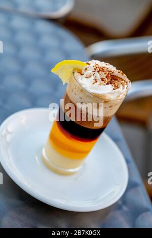 Detail eines Kaffees in Kombination mit Whisky Condensed Milk Zimtcreme und Zitrone in einer Glaskasse auf einer Terrasse Stockfoto