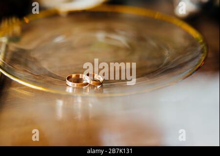 Zwei goldene runde Ringe auf einer großen, glitzernden Goldplatte. Stockfoto