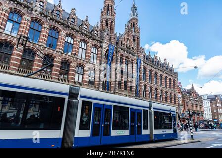 Amsterdam, Niederlande - 7. September 2018: Fassade eines Magna plaza Einkaufszentrums (ehemaliges Amsterdam Main Post Office) mit einer Straßenbahn und Menschen in der Umgebung Stockfoto