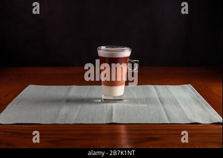 Isolierter Cappuccino, frisch in eine Glaskasse gebrüht. holztisch, Stockfoto