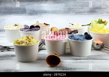 Verschiedene Eissorten mit frischen Blaubeeren, Erdbeeren, Kiwi, Zitrone und Vanille auf rustikalem Hintergrund. Sommer und süßes Eis Stockfoto