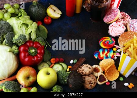 Gesunde oder ungesunde Lebensmittel. Konzeptfoto von gesunden und ungesunden Lebensmitteln. Obst und Gemüse im Vergleich zu Donuts, Süßigkeiten und Burgern auf dem Tisch Stockfoto