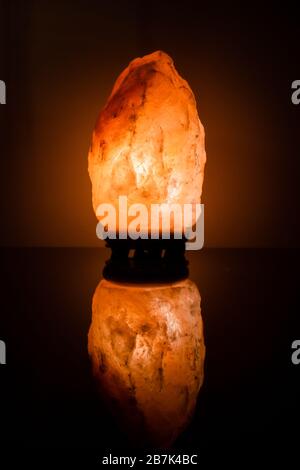 Himalaya-Salzlampe auf schwarzem Hintergrund reflektiert Stockfoto