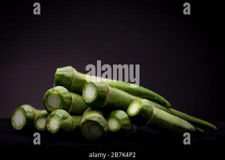 Viele Okra- oder Damenfinger Gemüse in grafischem Moody Rahmen. Studio Low Key Stillleben von essbaren Lebensmitteln im Rampenlicht Stockfoto