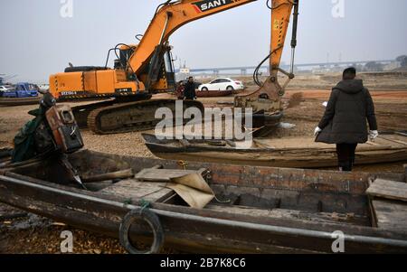 Ein Arbeiter sieht sich ein Fischerboot an, das am 30. Dezember 2019 in der Nähe des Dongting Lake in der Stadt Yueyang, der zentralchinesischen Provinz Hunan, abgebaut wird. Ein 10-jähriger Fisch Stockfoto