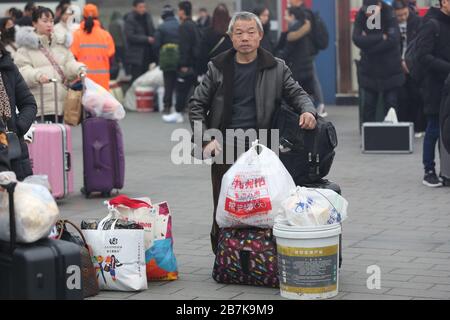 Die Passagiere tragen einen Plastikeimer, der ihr Gepäck enthält, und bereiten sich auf die Fahrt mit dem Zug vor, der nach Hause am Bahnhof Xi'an, der Stadt Xi'an, in Richtung Norden fährt Stockfoto