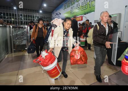 Die Passagiere tragen einen Plastikeimer, der ihr Gepäck enthält, und bereiten sich darauf vor, an Bord des Zuges zu gehen, der zu Hause am Bahnhof Shenzhen, der Stadt Shenzhen, liegt Stockfoto