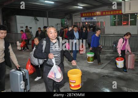 Die Passagiere tragen einen Plastikeimer, der ihr Gepäck enthält, und bereiten sich darauf vor, an Bord des Zuges zu gehen, der zu Hause am Bahnhof Shenzhen, der Stadt Shenzhen, liegt Stockfoto