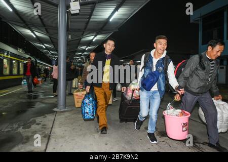 Die Passagiere tragen einen Plastikeimer, der ihr Gepäck enthält, und bereiten sich darauf vor, an Bord des Zuges zu gehen, der zu Hause am Bahnhof Shenzhen, der Stadt Shenzhen, liegt Stockfoto