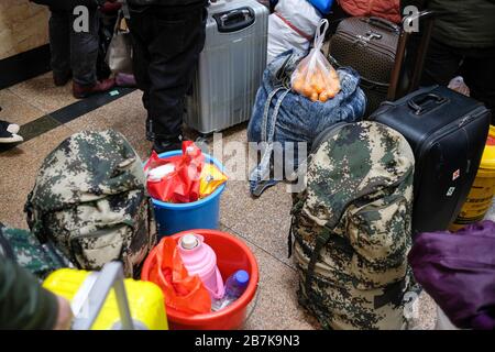 Die Passagiere tragen einen Plastikeimer, der ihr Gepäck enthält, und bereiten sich darauf vor, an Bord des Zuges zu gehen, der zu Hause am Bahnhof von Peking, Peking, China, 1 fährt Stockfoto