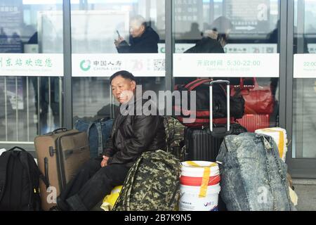 Die Passagiere tragen einen Plastikeimer, der ihr Gepäck enthält, und bereiten sich darauf vor, an Bord des Zuges zu gehen, der zu Hause am Bahnhof Hangzhoudong, Hangzhou Cit, fährt Stockfoto