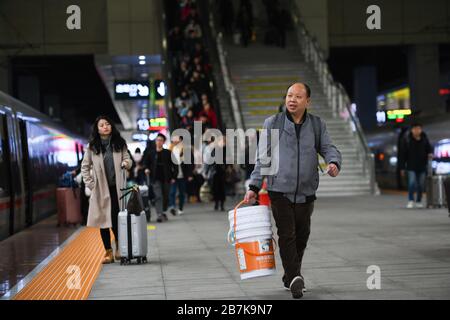 Die Passagiere tragen einen Plastikeimer, der ihr Gepäck enthält, und bereiten sich auf die Fahrt mit dem Zug vor, der nach Hause zum Bahnhof Chongqingbei, Chongqing, C fährt Stockfoto