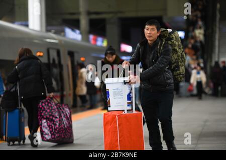 Die Passagiere tragen einen Plastikeimer, der ihr Gepäck enthält, und bereiten sich auf die Fahrt mit dem Zug vor, der nach Hause zum Bahnhof Chongqingbei, Chongqing, C fährt Stockfoto